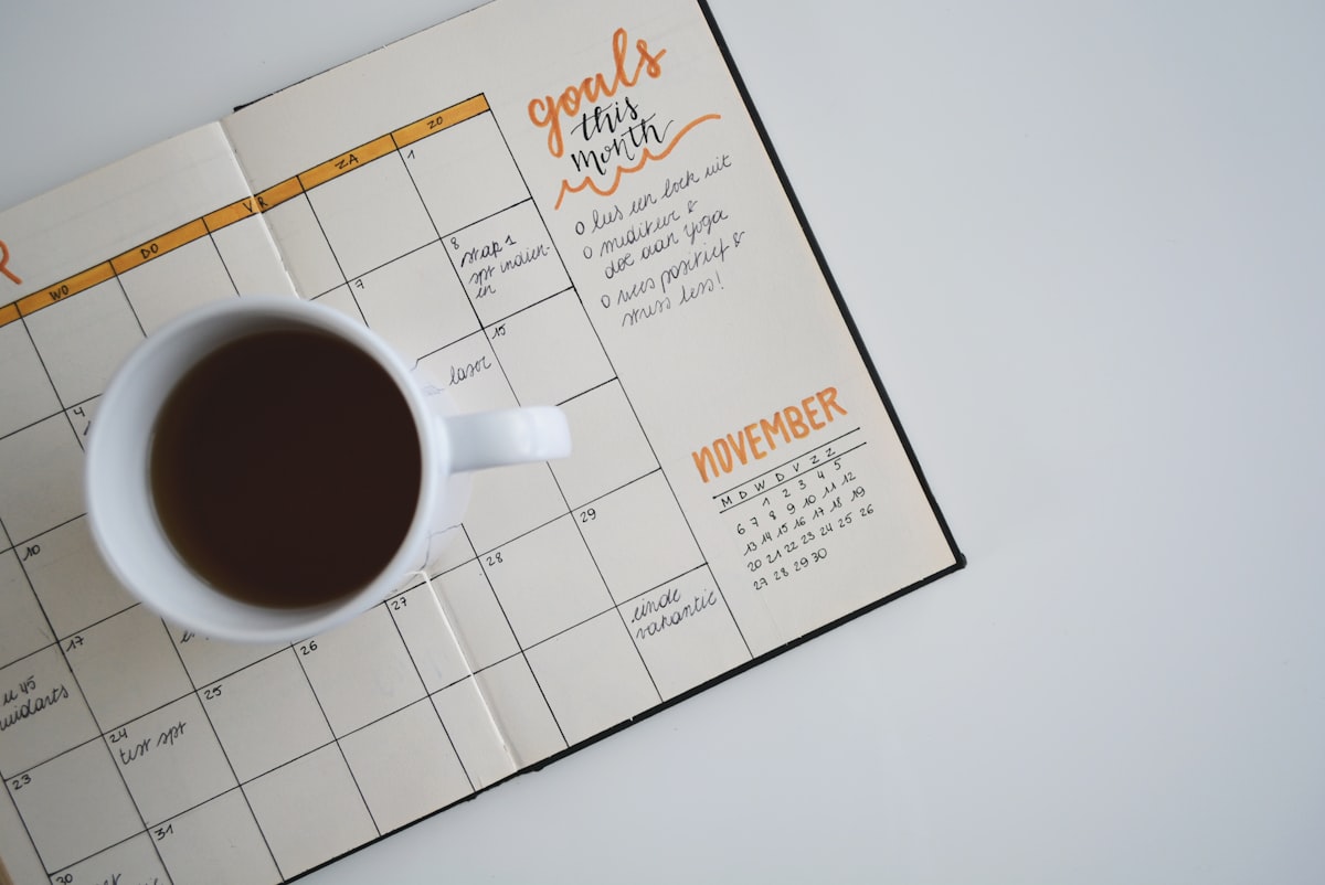 Open planner with a pen on a light wooden desk